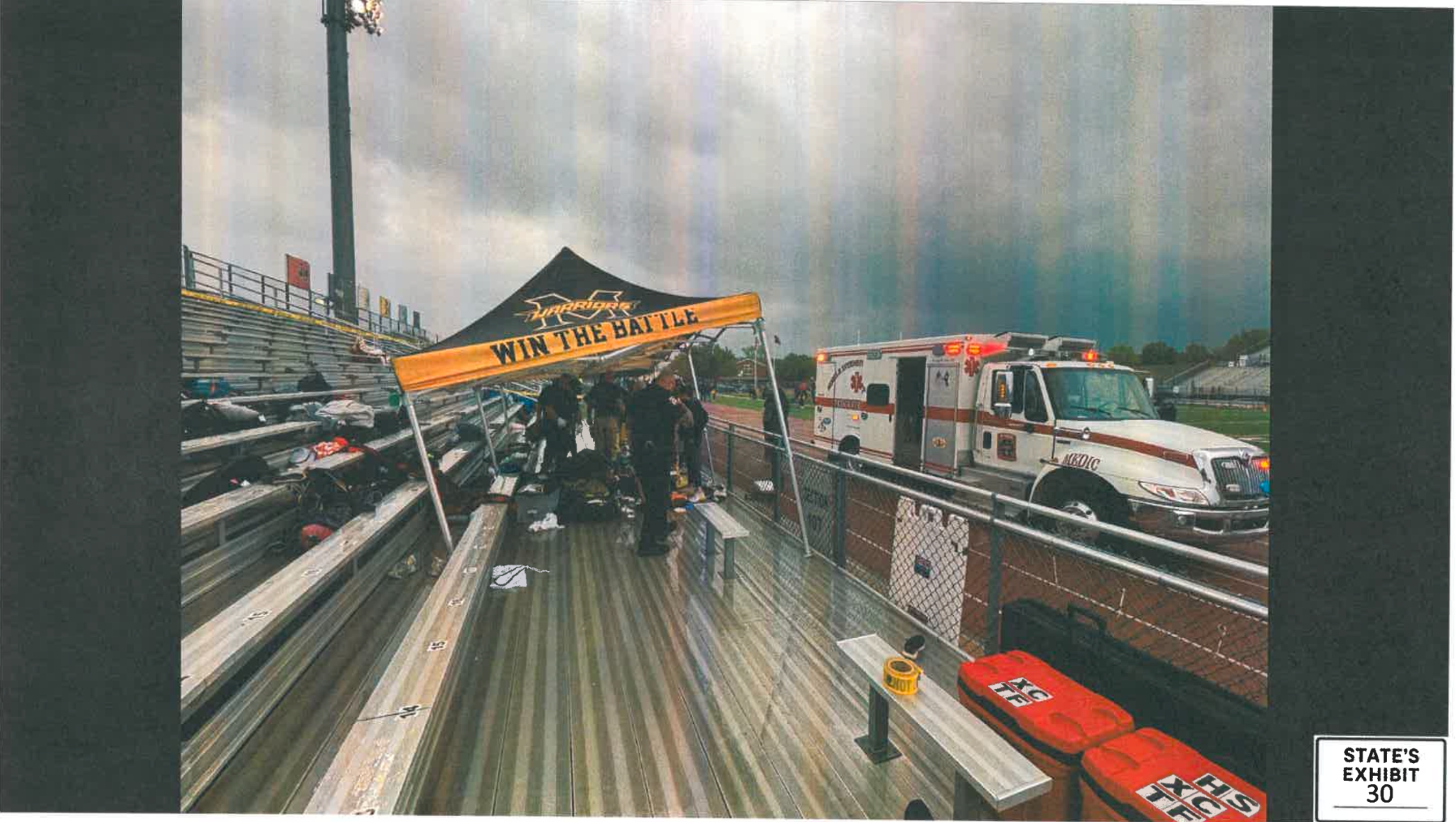 Emergency responders and an ambulance beside team tents in the stadium bleachers